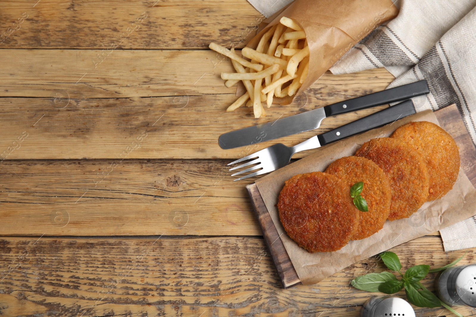 Photo of Delicious fried breaded cutlets served on wooden table, flat lay. Space for text