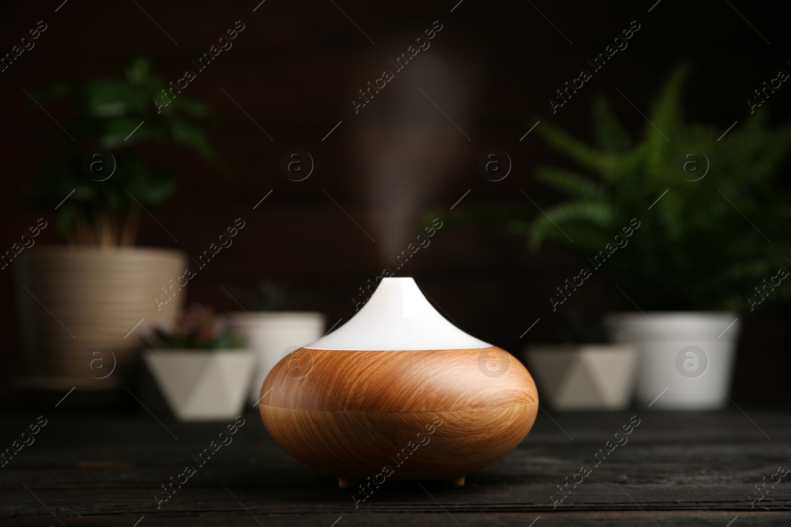 Photo of Composition with modern essential oil diffuser on black wooden table against dark background, space for text