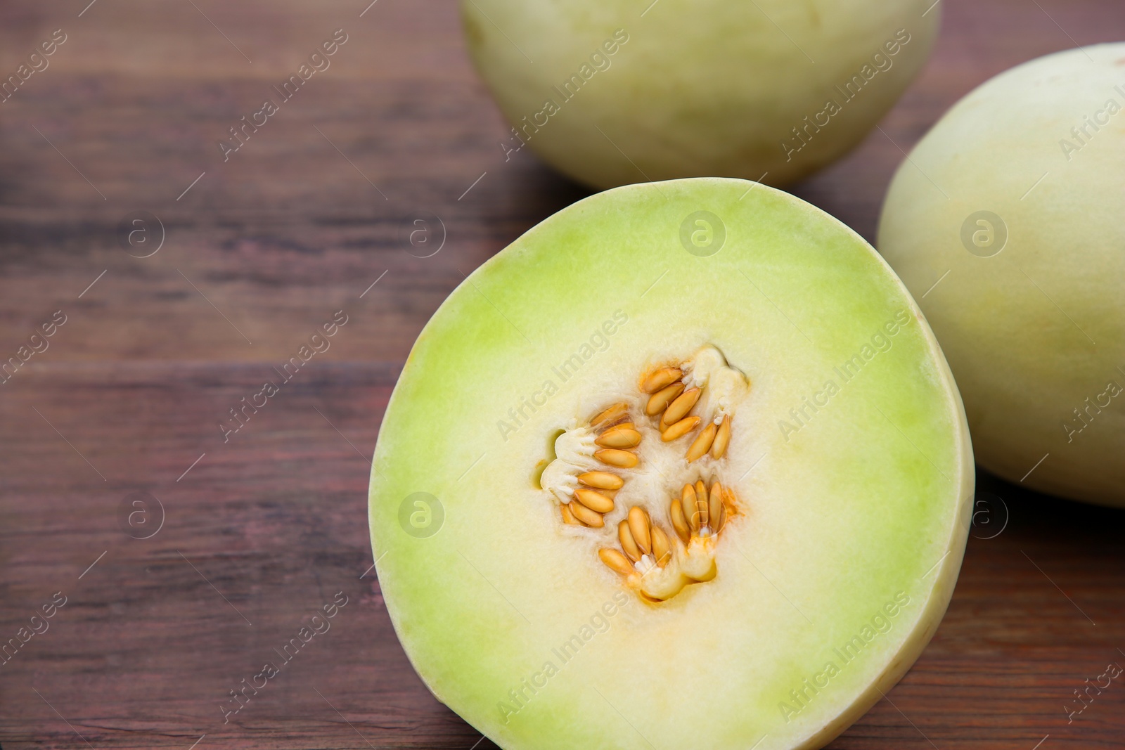 Photo of Whole and cut fresh ripe melons on wooden table, closeup. Space for text