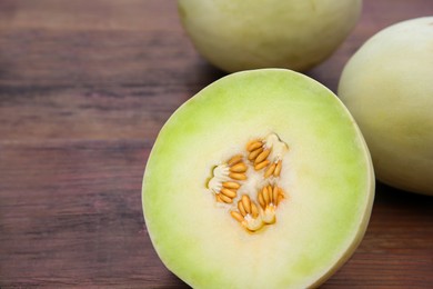 Photo of Whole and cut fresh ripe melons on wooden table, closeup. Space for text