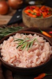 Photo of Fresh raw minced meat and rosemary in bowl on table, closeup