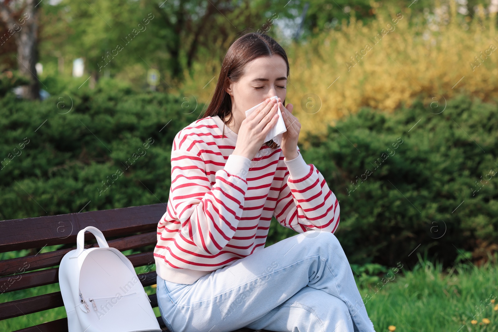 Photo of Woman with napkin suffering from seasonal allergy on bench in park