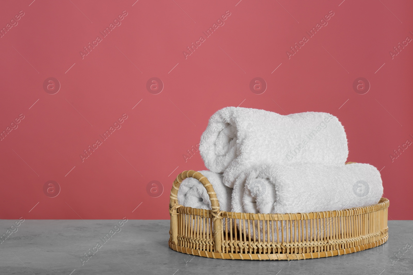 Photo of Rolled fresh towels on light grey stone table. Space for text