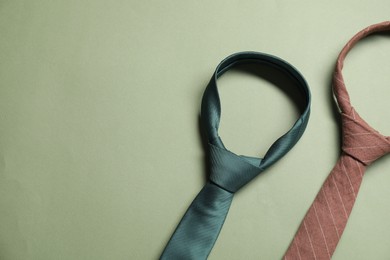 Photo of Different neckties on light green background, top view. Space for text