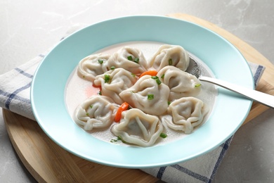 Photo of Plate of tasty dumplings in broth served on grey marble table