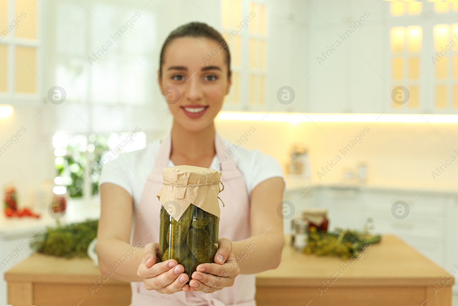 Photo of Woman holding jar of pickles in kitchen, focus on hands. Space for text