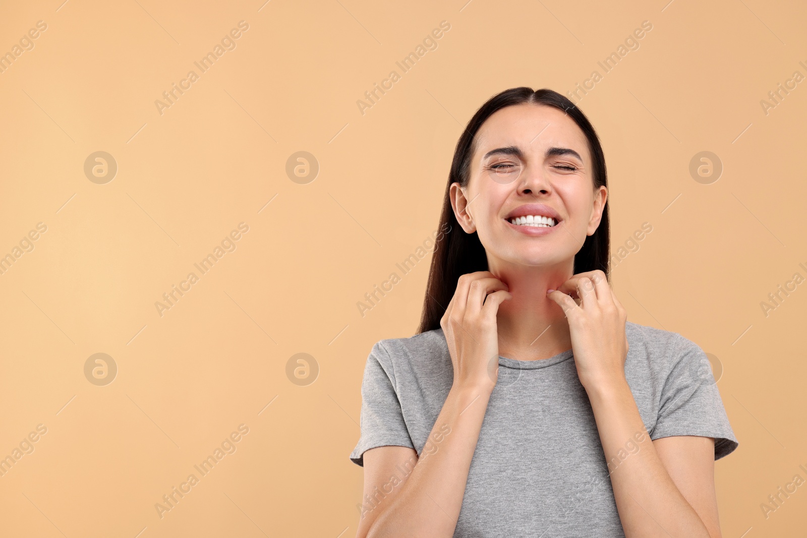 Photo of Suffering from allergy. Young woman scratching her neck on beige background, space for text