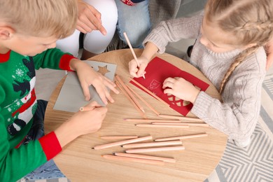 Photo of Cute children with their parents making beautiful Christmas greeting cards at home