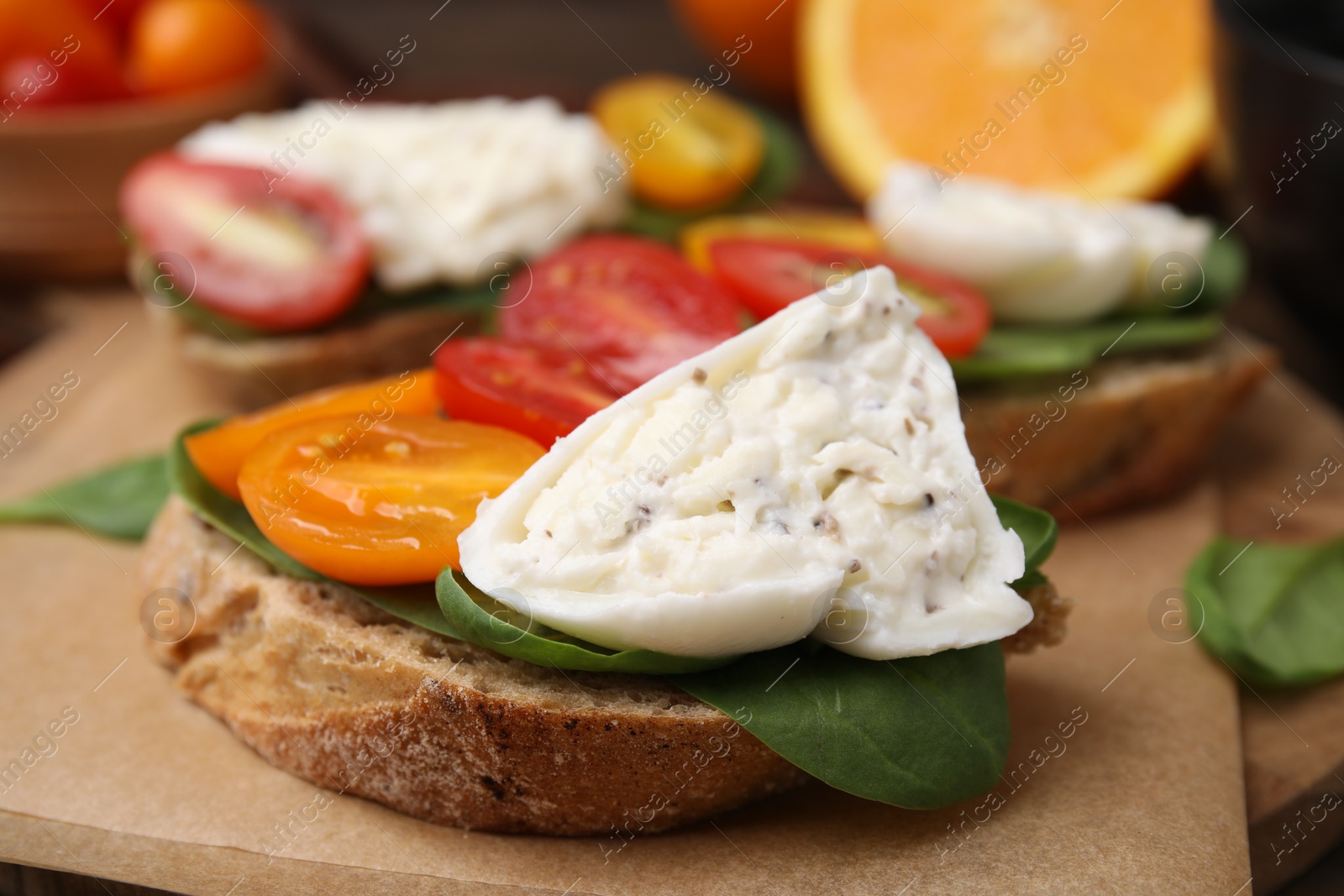 Photo of Delicious sandwich with burrata cheese and tomatoes on board, closeup