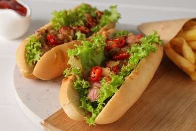 Photo of Tasty hot dogs with chili, lettuce and sauce on white table, closeup