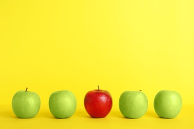 Photo of Row of green apples with red one on color background. Be different