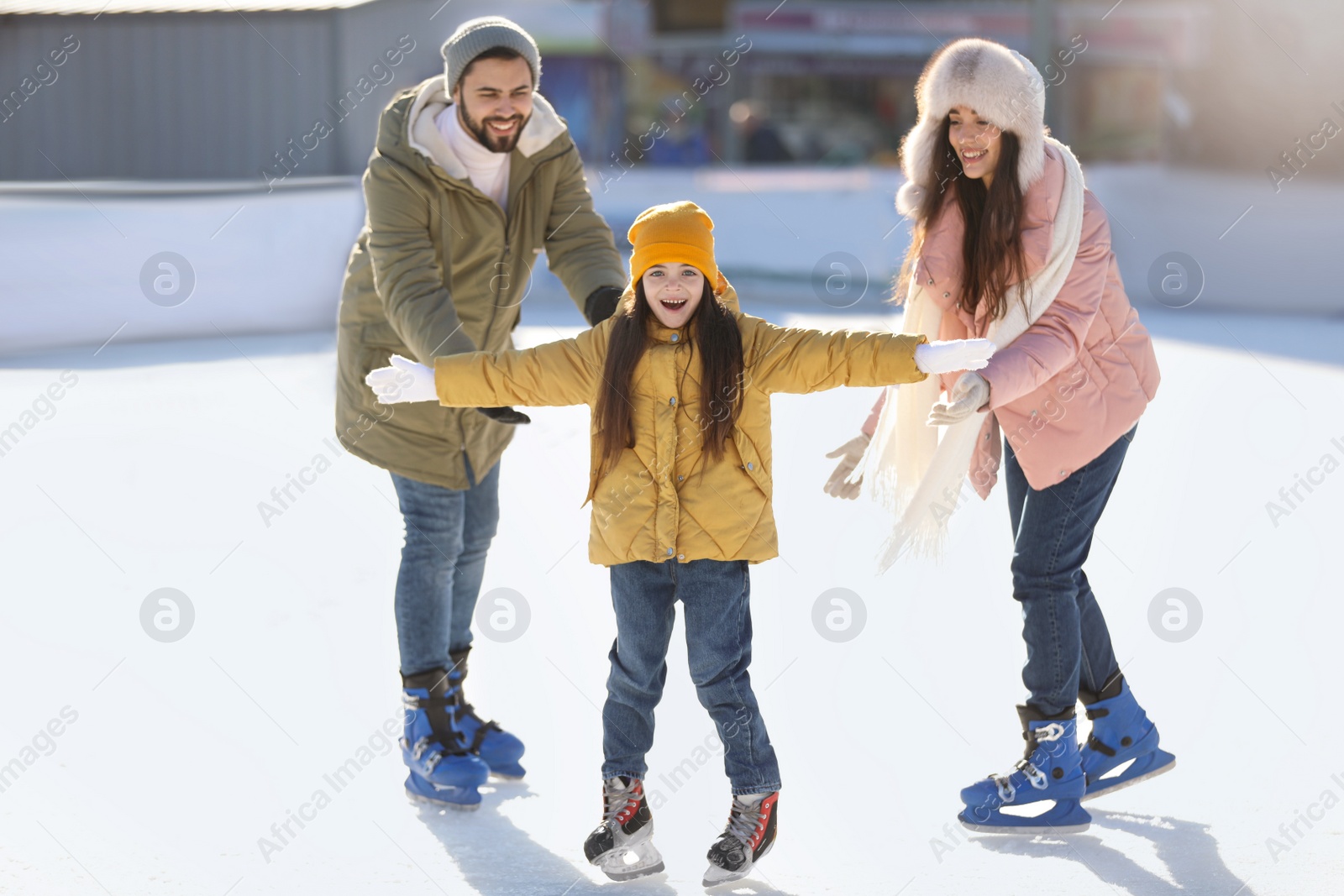 Image of Happy family spending time together at outdoor ice skating rink