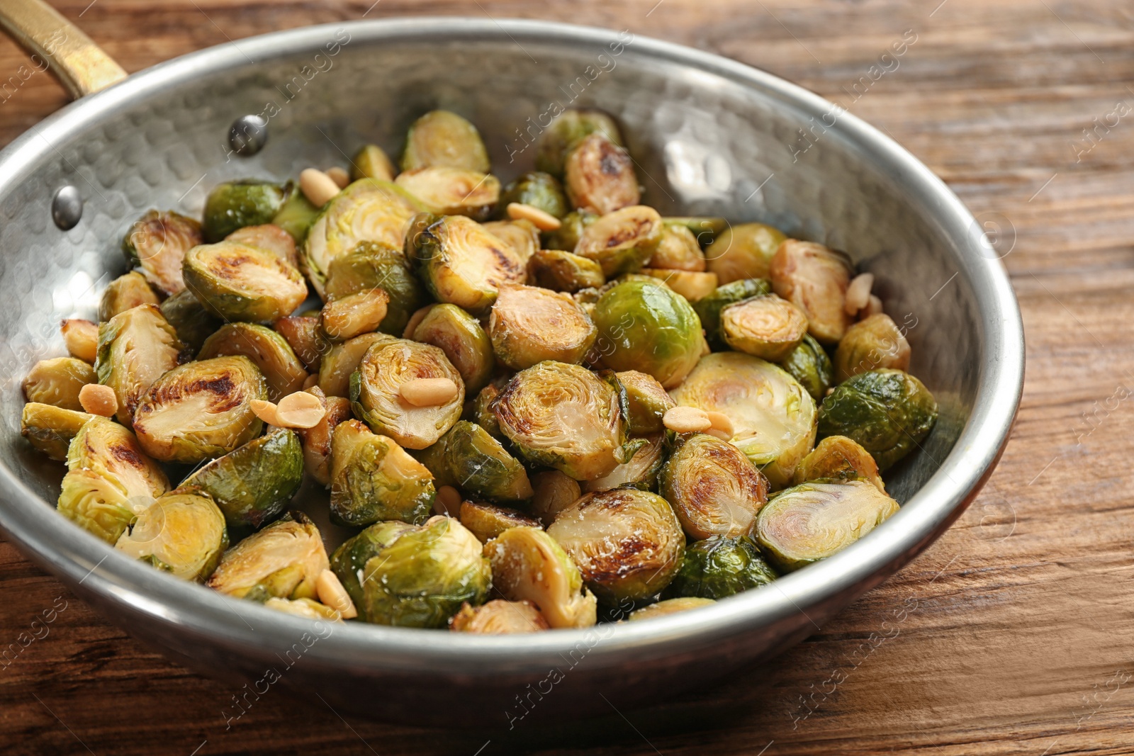 Photo of Delicious roasted brussels sprouts with peanuts on wooden table, closeup