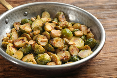 Photo of Delicious roasted brussels sprouts with peanuts on wooden table, closeup