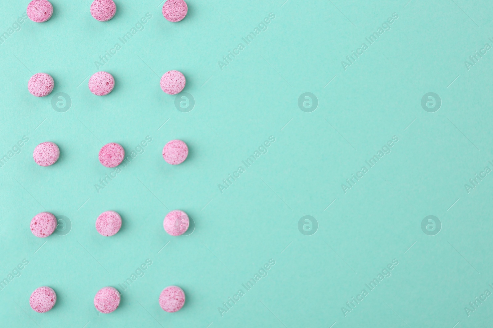 Photo of Many pink vitamin pills on turquoise background, flat lay. Space for text