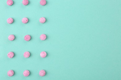 Photo of Many pink vitamin pills on turquoise background, flat lay. Space for text