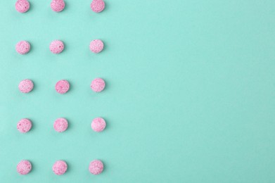 Many pink vitamin pills on turquoise background, flat lay. Space for text