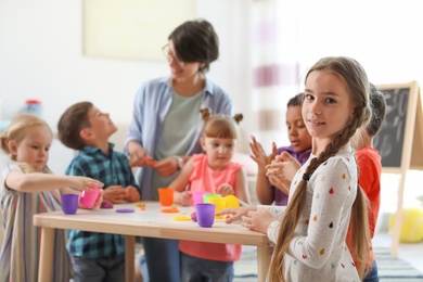 Photo of Young woman playing with little children indoors