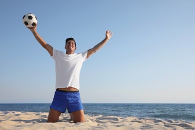 Photo of Man with football ball on beach. Space for text