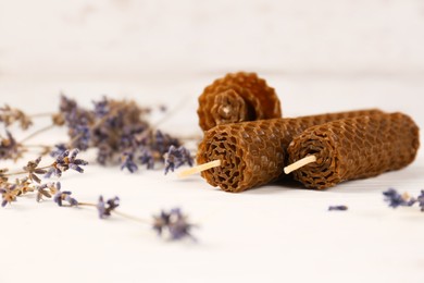 Photo of Stylish elegant beeswax candles and lavender on white wooden table