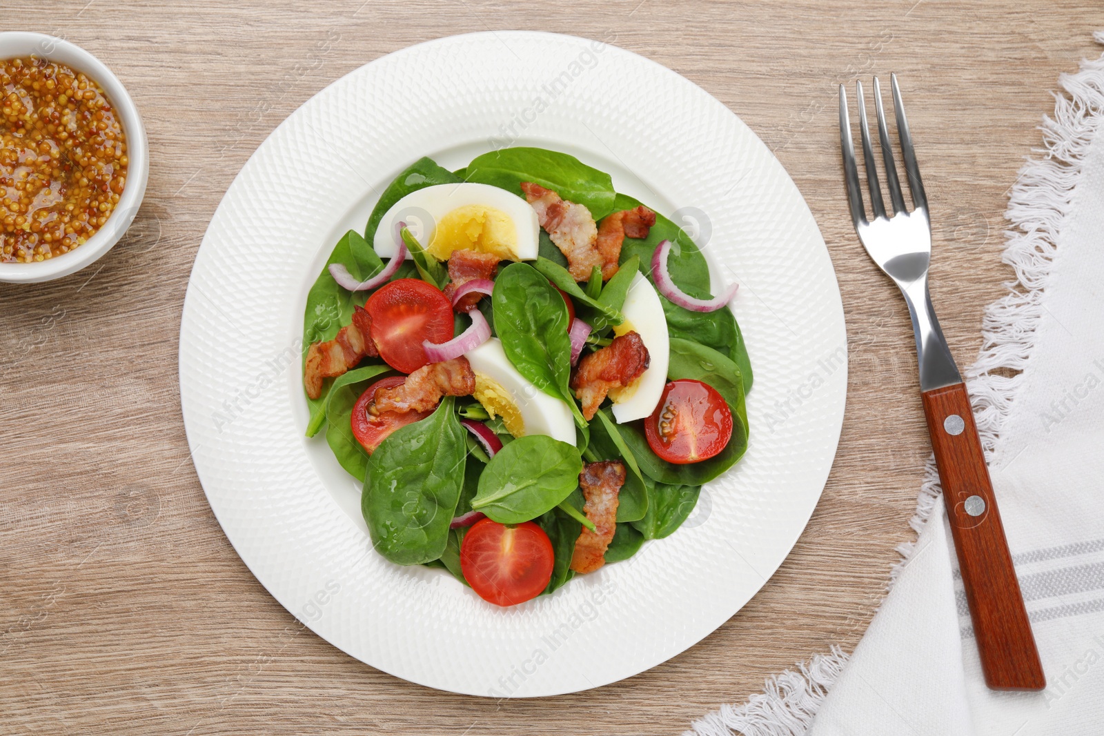 Photo of Delicious salad with boiled egg, bacon and vegetables served on wooden table, flat lay