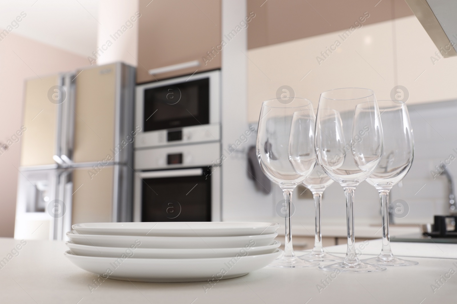 Photo of Stack of clean dishes and glasses on table in kitchen