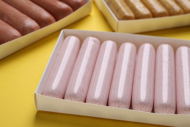 Different vegan sausages on yellow background, closeup