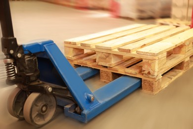 Image of Modern manual forklift with wooden pallets in warehouse, closeup