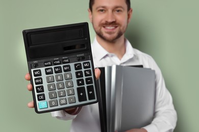 Happy accountant with calculator and folders on olive background, selective focus