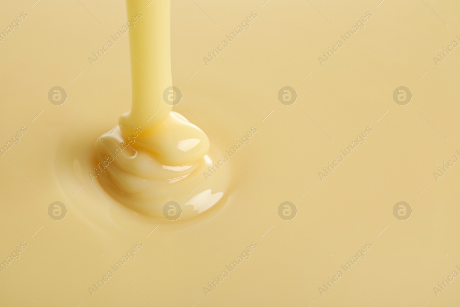 Photo of Tasty pouring condensed milk as background, space for text. Dairy product