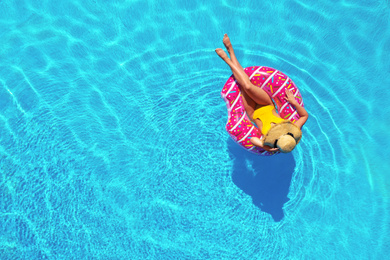 Image of Young woman with inflatable ring in swimming pool, top view. Space for text