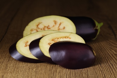 Photo of Cut purple eggplant on wooden table, closeup