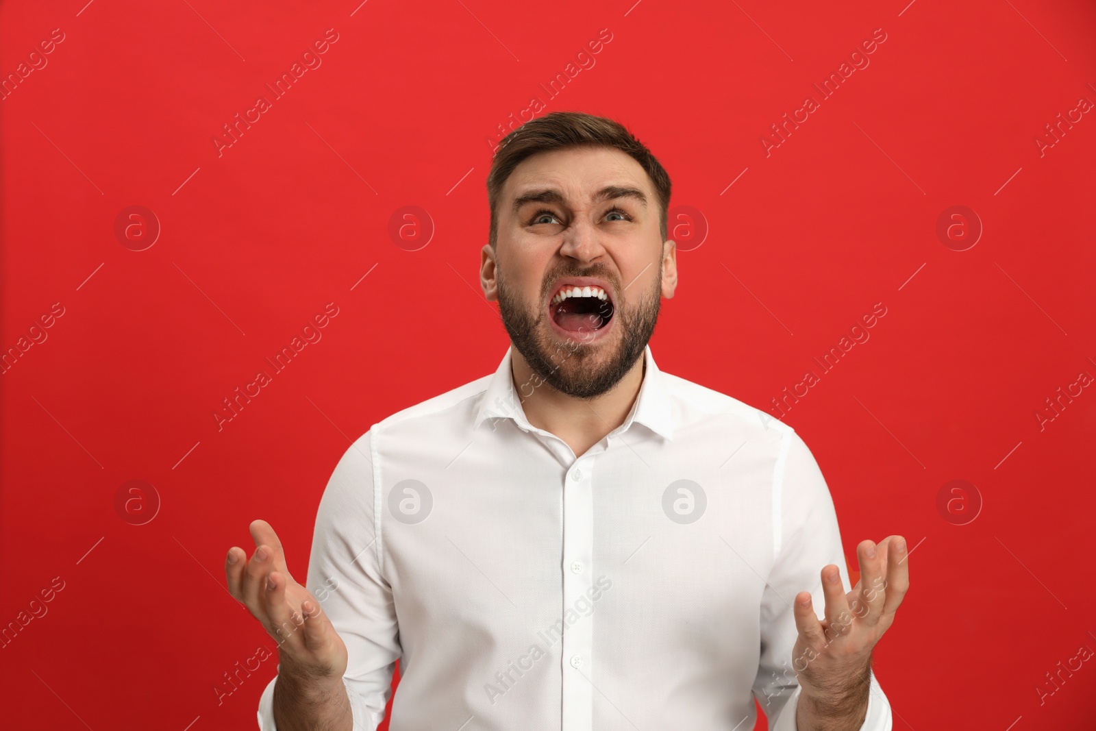 Photo of Angry young man on red background. Hate concept