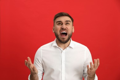 Photo of Angry young man on red background. Hate concept