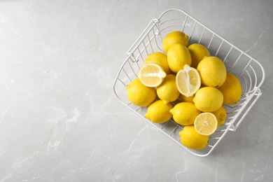 Photo of Wire basket with lemons on gray table, top view