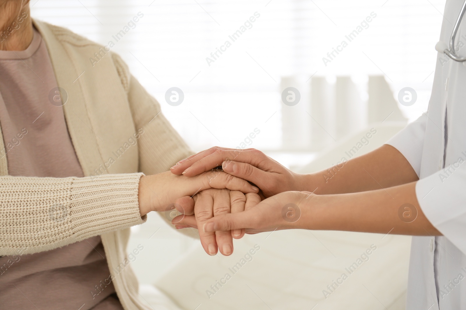 Photo of Doctor holding senior patient's hands in office , closeup