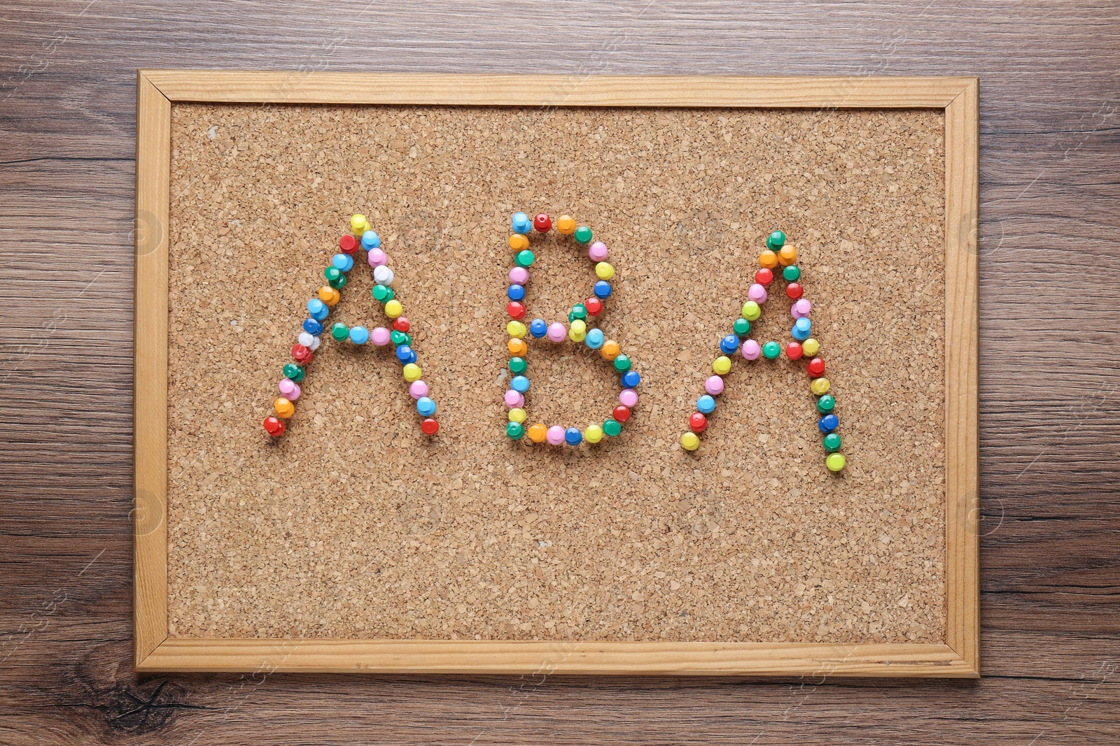 Photo of Applied behavior analysis concept. Corkboard with abbreviation ABA made of colorful pins on wooden table, top view