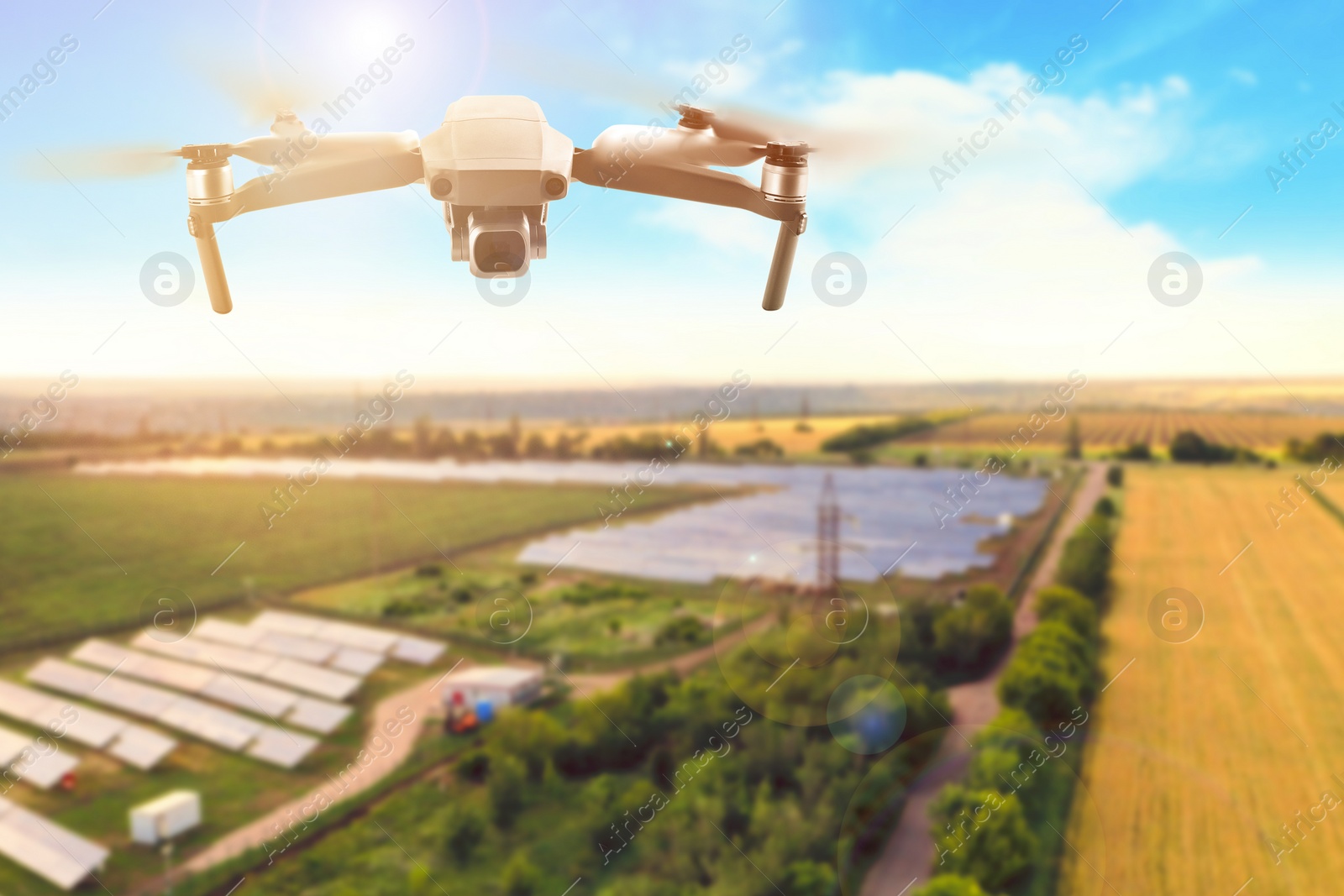 Image of Modern drone flying over fields on sunny day. Aerial survey