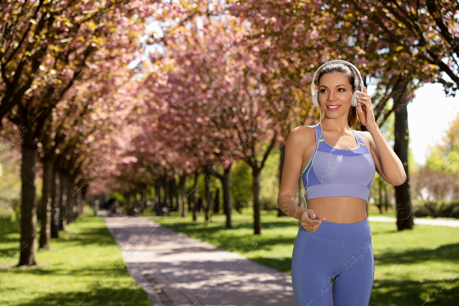 Photo of Woman with headphones on morning run in park, space for text. Fitness lifestyle