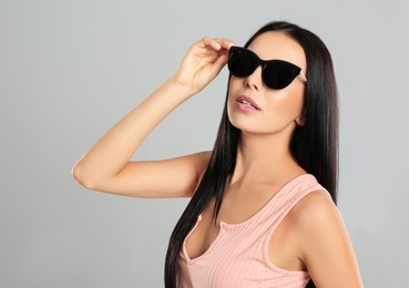 Photo of Beautiful woman wearing sunglasses on grey background