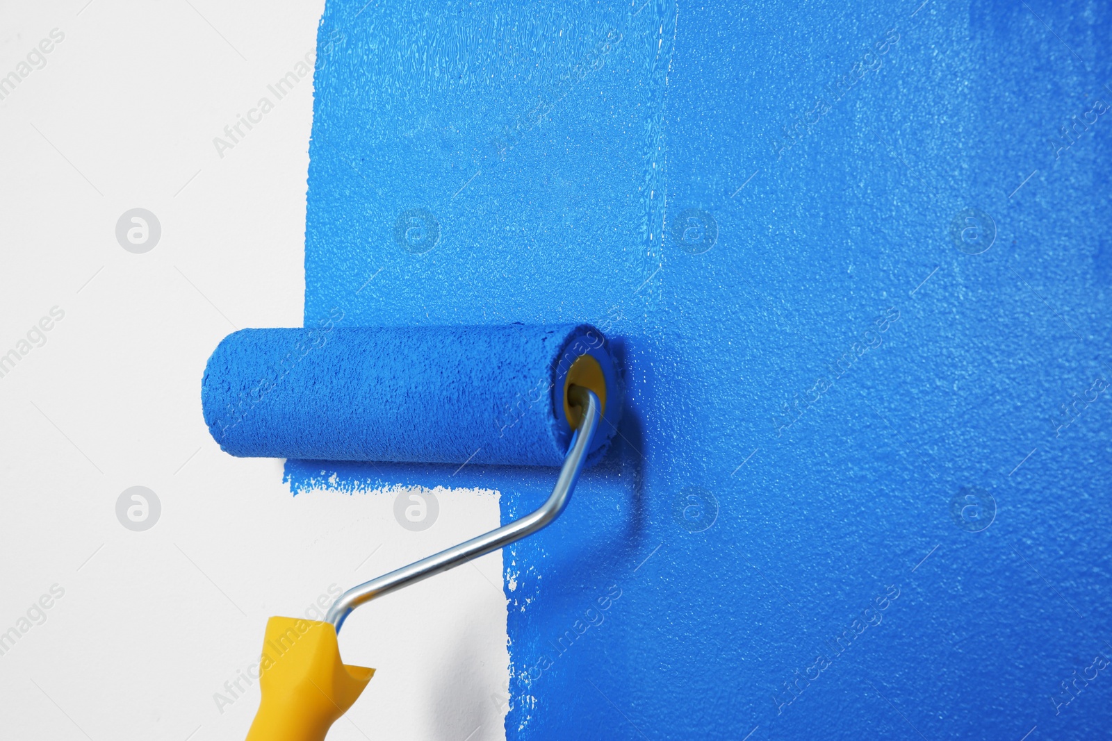 Photo of Painting white wall with blue dye, closeup. Interior renovation