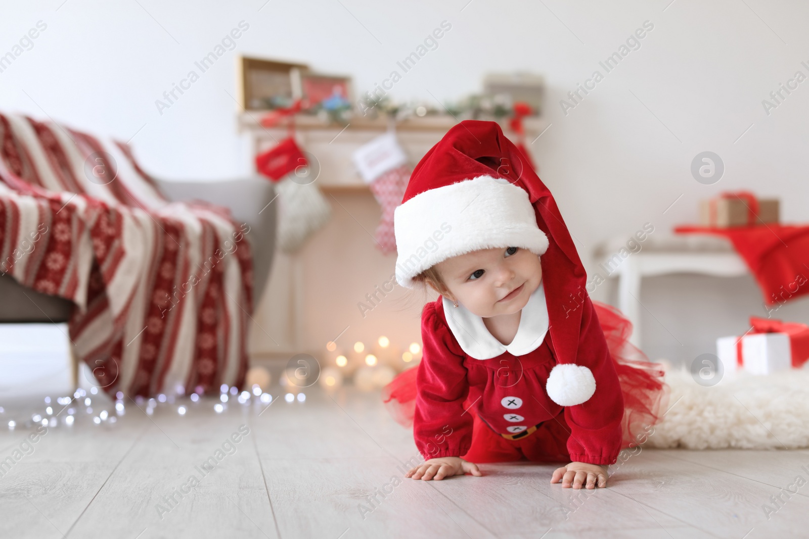 Photo of Cute baby in Christmas costume on floor at home