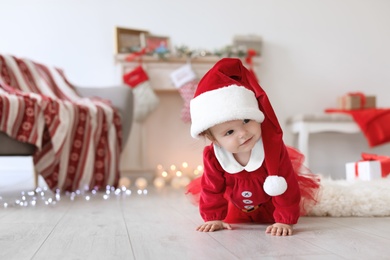 Photo of Cute baby in Christmas costume on floor at home