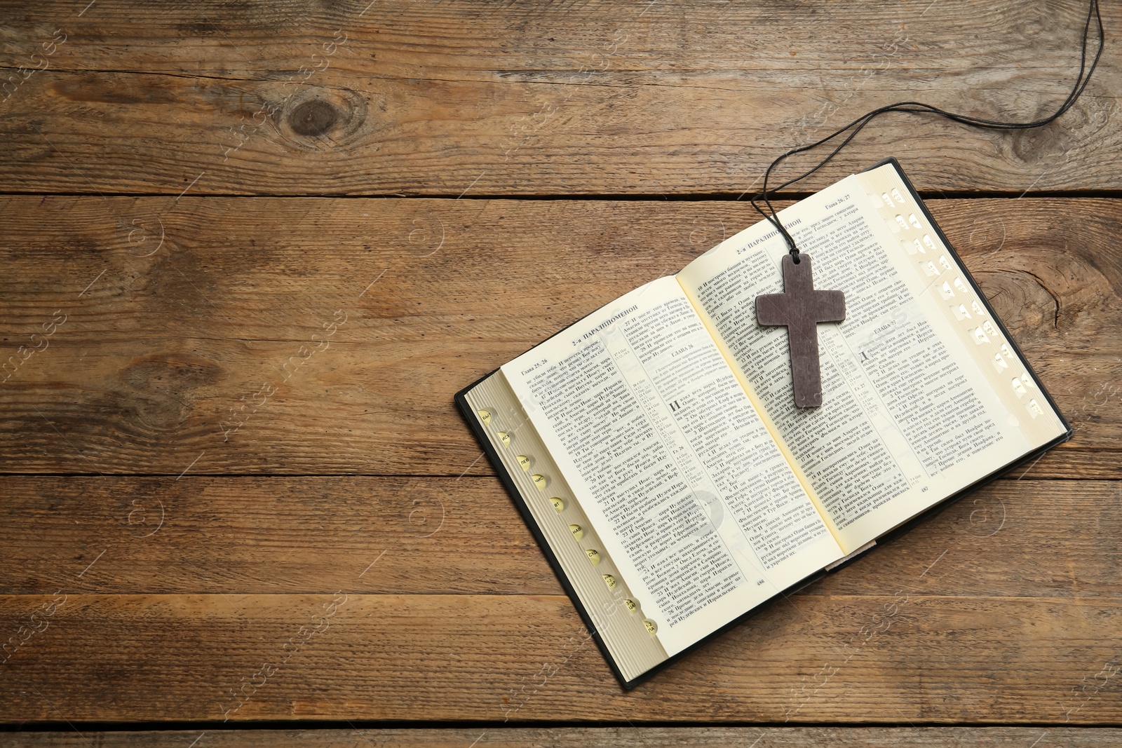 Photo of MYKOLAIV, UKRAINE - DECEMBER 20, 2021: Christian cross and Bible on wooden table, top view. Space for text