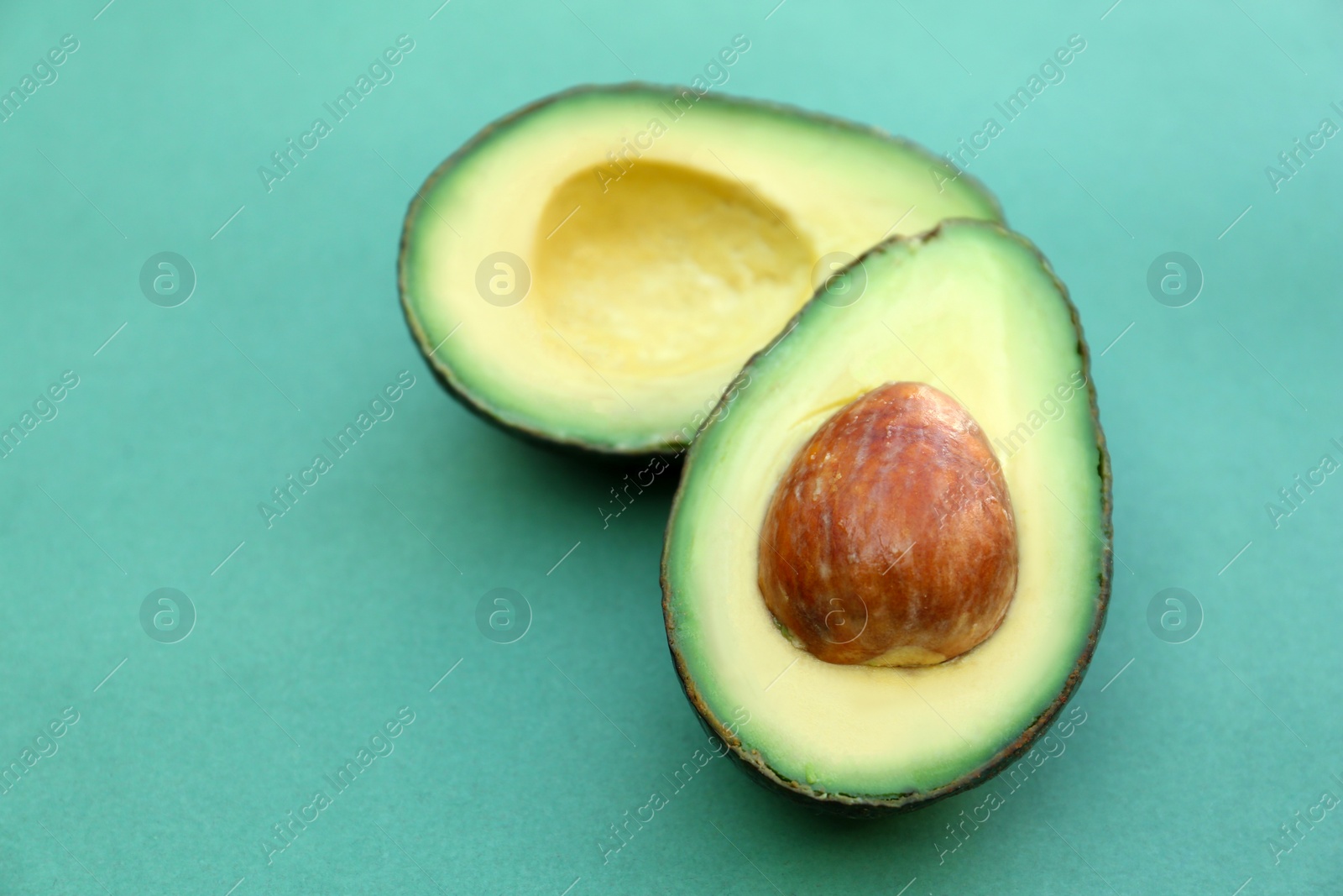 Photo of Tasty cut avocado on turquoise background, closeup