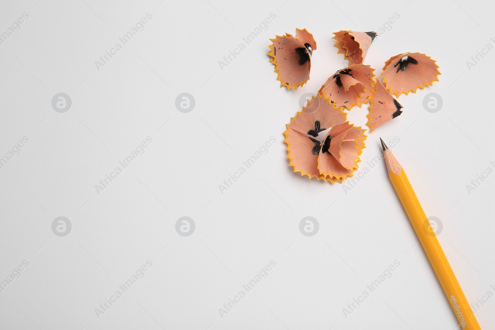 Photo of Sharp graphite pencil and shavings on white background, top view. Space for text