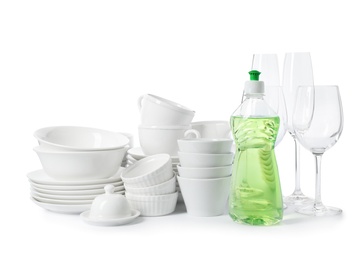 Photo of Clean tableware and bottle of detergent on white background. Washing dishes