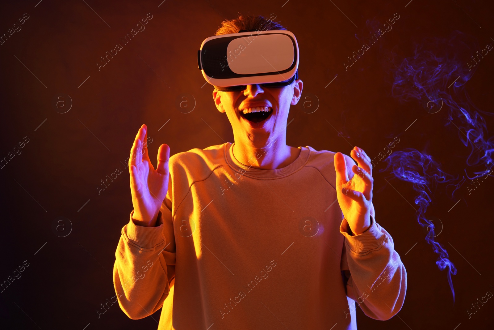 Photo of Young man with virtual reality headset on brown background