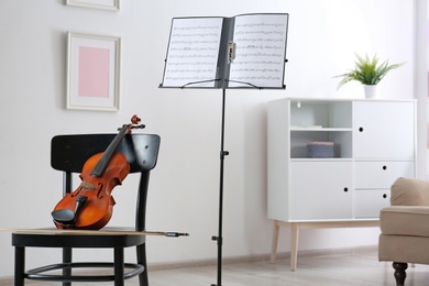 Photo of Violin, chair and note stand with music sheets in room