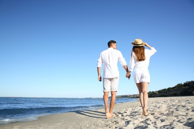 Photo of Lovely couple walking on beach, back view. Space for text